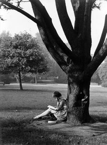 361164 Afbeelding van een lezend meisje onder een boom, vermoedelijk in het park Oog in Al te Utrecht.